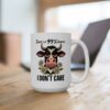White ceramic mug with a grumpy cartoon cow and daisies, reading 