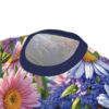 Seamless all over print t-shirt displays vibrant pink, blue, white flowers, green foliage, sublimation graphic, navy crewneck.