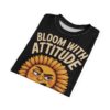 Black t-shirt, all over print, distressed texture, grumpy sunflower graphic, orange face, yellow petals, cream text 'BLOOM WITH ATTITUDE', crewneck, folded.