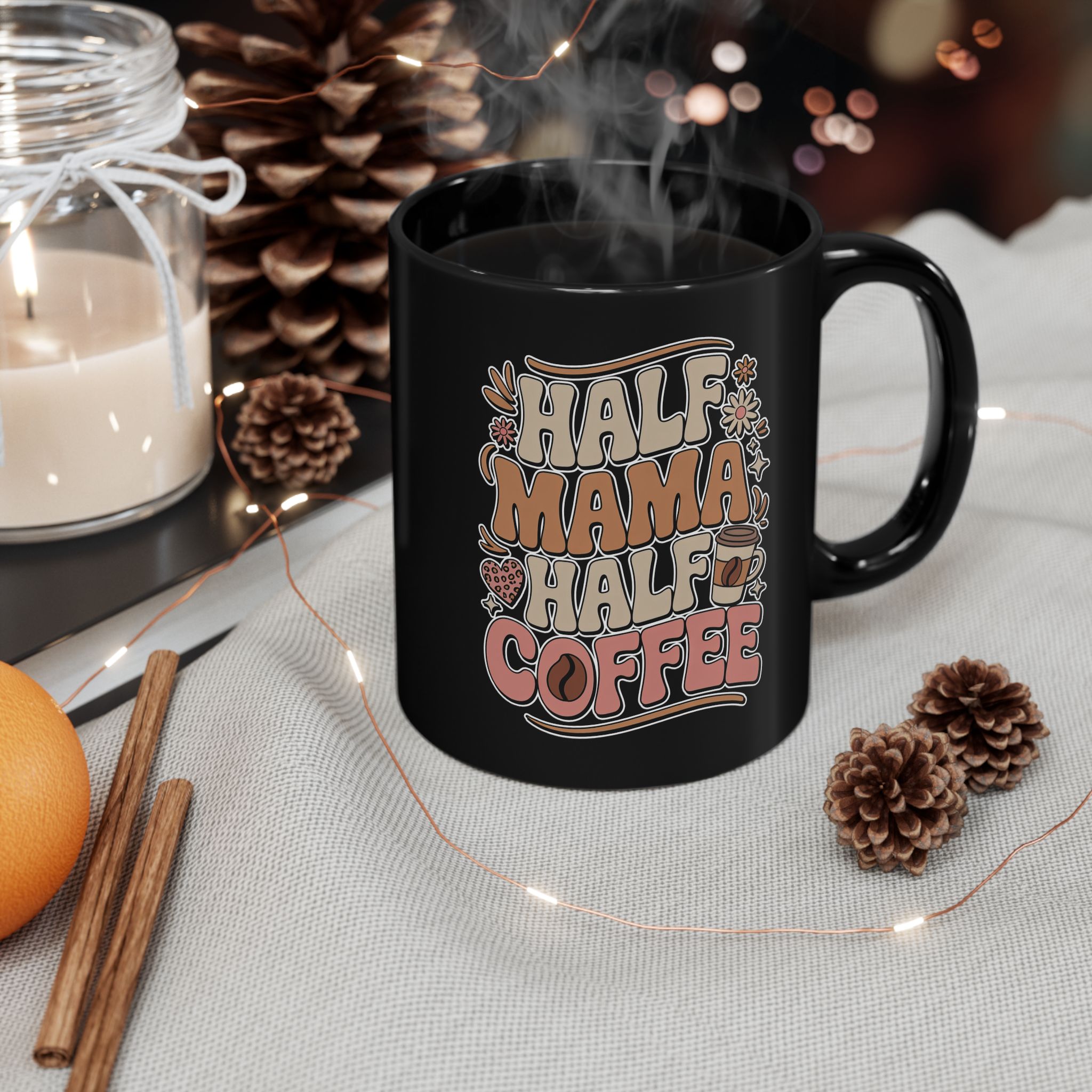 Black ceramic mug with "Half Mama Half Coffee" text and floral graphics, steaming coffee inside.