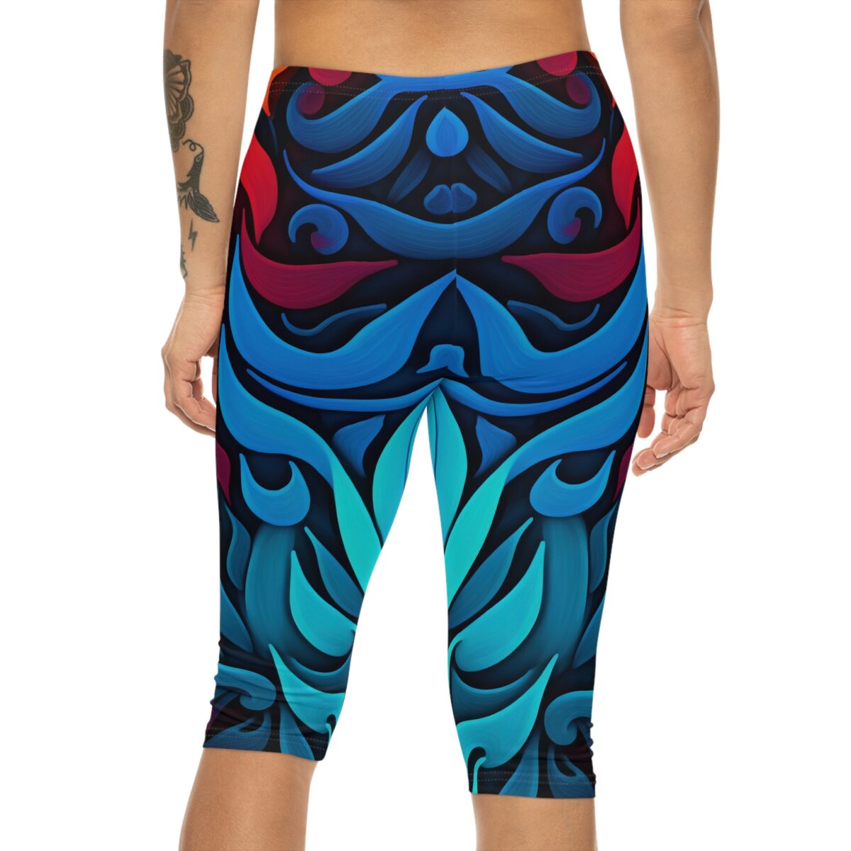 Close-up back view of a person wearing capri leggings featuring an intricate abstract design of flowing blue and red shapes.
