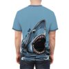 Blue and grey tones with black accents cover this full print shirt, depicting a great white shark emerging from dark, stylized water with sharp teeth bared.