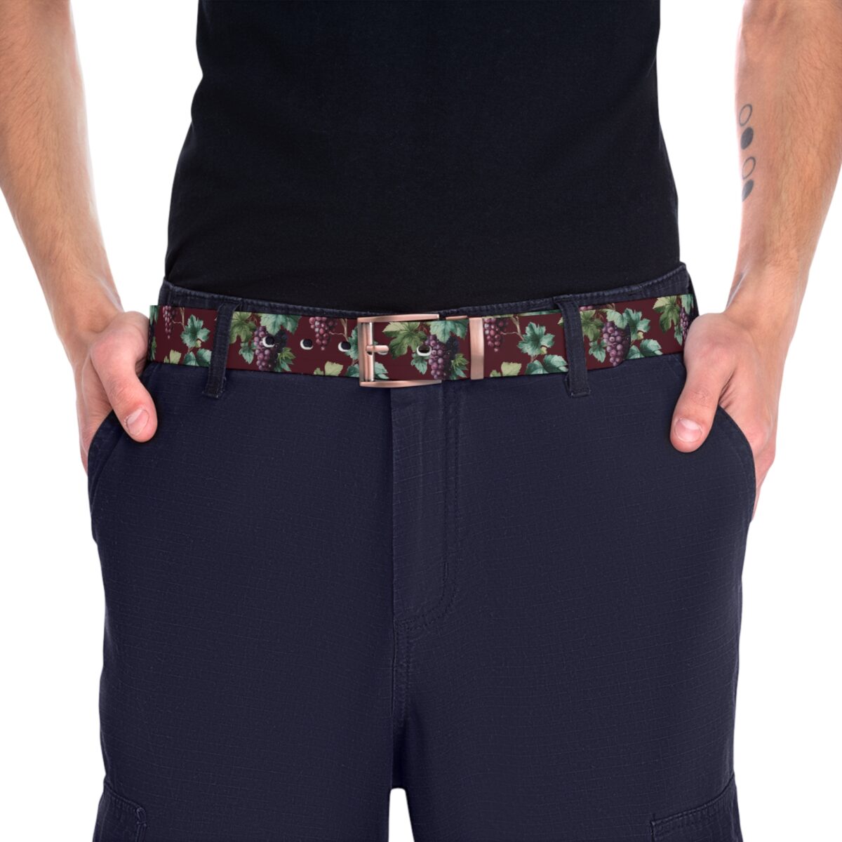 A men's belt featuring a seamless all over print of dark purple grapes on a burgundy background with green leaves.