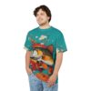 Vibrant teal with a large trout, orange flowers, and stylized clouds cover this patterned tee shirt, ready for casual wear.