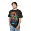 A snarling monkey in an orange cap, green jacket, pink shirt, and purple pants adorns this graphic tee with a neon blue glow.