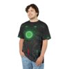 Dark grey and black metallic textures with glowing green and red circuitry cover this graphic streetwear tee, depicting a central glowing green circular core and intricate paneling.