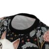 Black background with detailed floral patterns and a white cat's face, featuring pink roses and grey foliage.