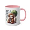 White ceramic mug with pink handle and interior, featuring a cute sloth holding a coffee cup and the text 