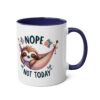 A white ceramic mug with a dark blue handle and interior, featuring a sleepy sloth in a hammock with 