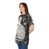 Black fabric with dark floral patterns, pink flowers, and a white cat covered in small leaves adorn this patterned tee shirt.