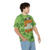 Green shamrocks and a subtle gradient pattern cover this graphic t-shirt, featuring bold text and a kissing lips graphic.