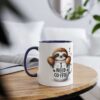 White ceramic mug with a navy blue handle and rim, featuring a cute sloth peeking out of a coffee cup with 