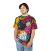 Vibrant yellow, orange, pink, purple, and white flowers surround a black cat with green eyes on this sublimation graphic tee.