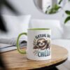 White ceramic mug with a green rim and handle, featuring a sleepy sloth illustration and the text 