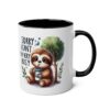 White ceramic mug with a black interior and handle, featuring a cute sloth illustration with the text 