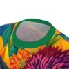 Vibrant reds, pinks, oranges, yellows, and blues cover this t-shirt, depicting a dense arrangement of blooming flowers and lush green leaves.