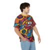 Bright yellow, orange, pink, and blue abstract shapes and cartoon characters cover this all over print t-shirt, depicting a skateboarding scene with a stylized figure.