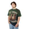 Dark green foliage covers this patterned tee shirt, featuring a sloth hanging from a branch with the words