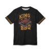 Black fabric with distressed texture and orange stripes on sleeves features a graphic of ribs on a grill with 