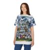 Blue and green watercolor clouds with rain streaks and a field of colorful tulips and daisies cover this patterned tee shirt, with white script reading