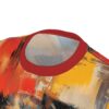 Close-up of a t-shirt featuring an abstract painting with bold brushstrokes in red, yellow, orange, black, and blue.
