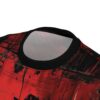 Close-up view of the collar and shoulder area of a t-shirt with an abstract grunge pattern. The pattern features vibrant red and black colors with a distressed, splattered, and streaked texture, resembling brush strokes or paint drips.