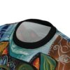 Close-up of the collar and upper chest area of a t-shirt featuring an abstract, colorful design with blue, green, yellow, and brown elements.