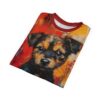 A t-shirt with a close-up, abstract painting of a puppy's face with expressive eyes, set against a vibrant, textured background of red, orange, and yellow.