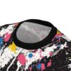 Black, white, pink, blue, and yellow paint splatters and drips cover this seamless pattern tee, with bold black strokes and fine speckles.