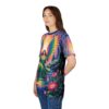 A woman wearing a t-shirt with a vibrant print of an angel with rainbow wings standing by a stream in a colorful forest.