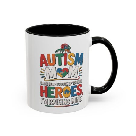 Autism Mom coffee mug with colorful puzzle heart graphic, stating 'Some people look up to their HEROES, I'M RAISING MINE'.