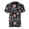 Pink and grey floral motifs with small red and gold accents cover this patterned tee shirt, set against a dark, speckled background.