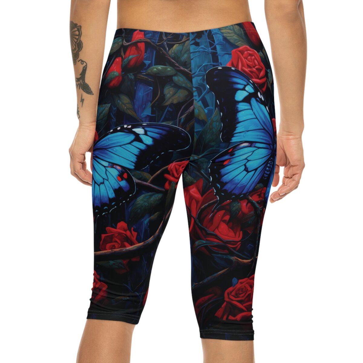 Capri leggings with a dark floral print featuring vibrant blue butterflies and red roses.