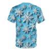 White dimensional snowflakes on a bright blue background cover this graphic streetwear tee, creating a festive winter scene.