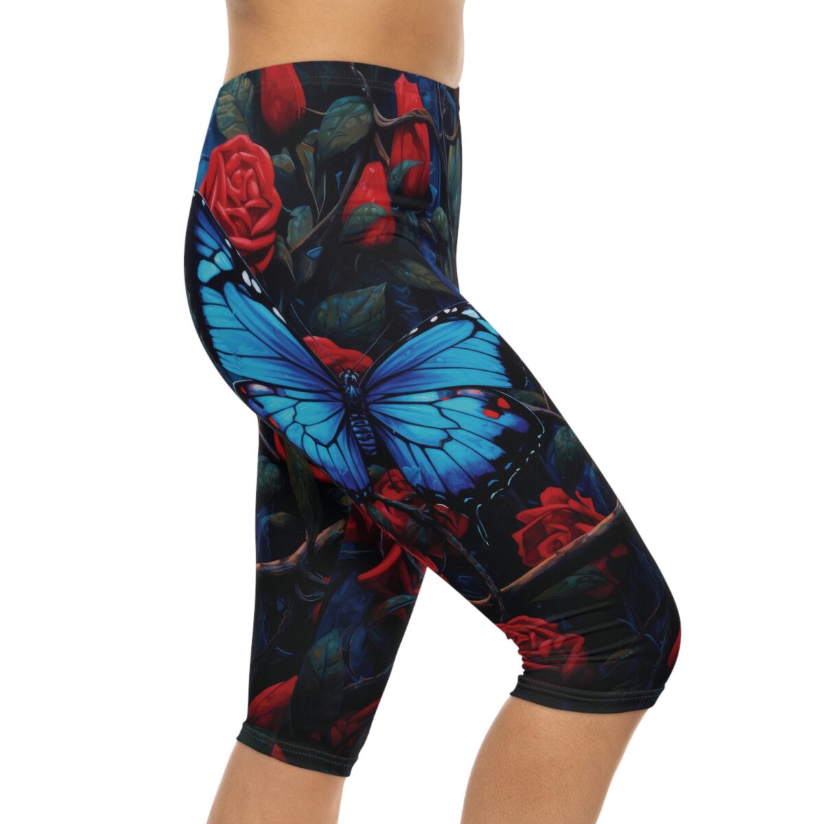 Capri leggings with a detailed black background featuring vibrant blue butterflies and red roses with dark green leaves.