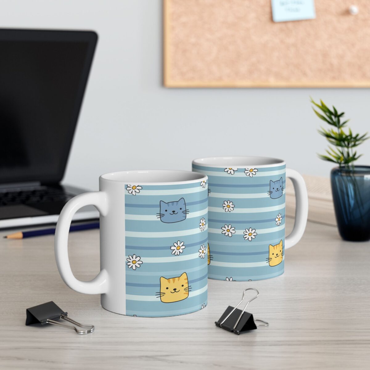 Two white ceramic mugs with a playful pattern of blue stripes, cute cat faces, and white daisies.