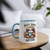 White ceramic mug with a blue interior and handle, featuring a cartoon sloth holding a cup and the text "BUSY DOING NOTHING."
