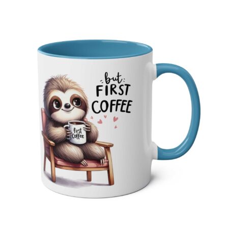 White ceramic mug with a blue interior and handle, featuring a watercolor illustration of a sloth holding a coffee cup and the text "but: FIRST COFFEE".