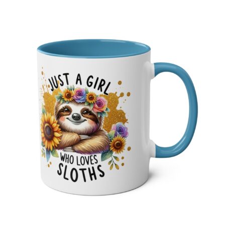 White ceramic mug with blue handle and rim, featuring a cute sloth with a floral crown and sunflowers, text reads "JUST A GIRL WHO LOVES SLOTHS".