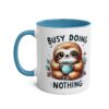 White ceramic mug with blue handle and interior, featuring a cartoon sloth holding a polka dot cup and text.