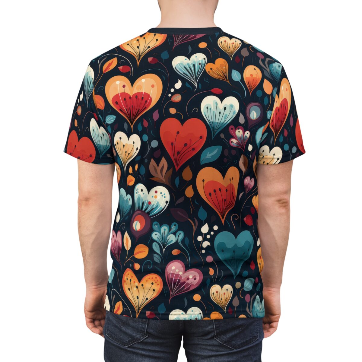 Back view of a person wearing a dark t-shirt with a repeating pattern of stylized heart-shaped flowers in vibrant colors like red, orange, yellow, and blue, accented with green leaves and small floral elements.