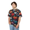 Red, orange, and teal hearts with floral accents cover this patterned tee shirt, with scattered dots and leaves on a dark background.