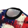 Close-up of a t-shirt featuring a distressed American flag design with grunge paint splatter effects and a black collar.