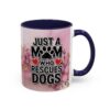 White ceramic mug with navy handle and interior, featuring pink floral watercolor background and bold text 'JUST A MOM WHO RESCUES DOGS'.