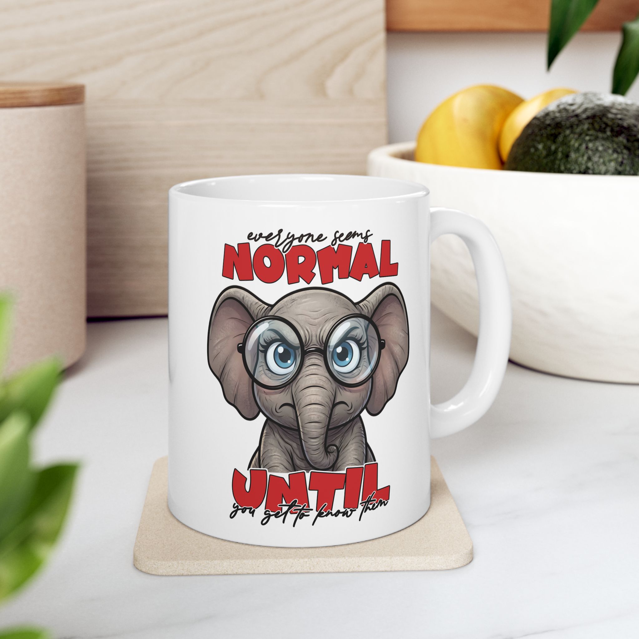 White mug with a cartoon elephant wearing glasses and the text "Everyone seems normal until you get to know them."