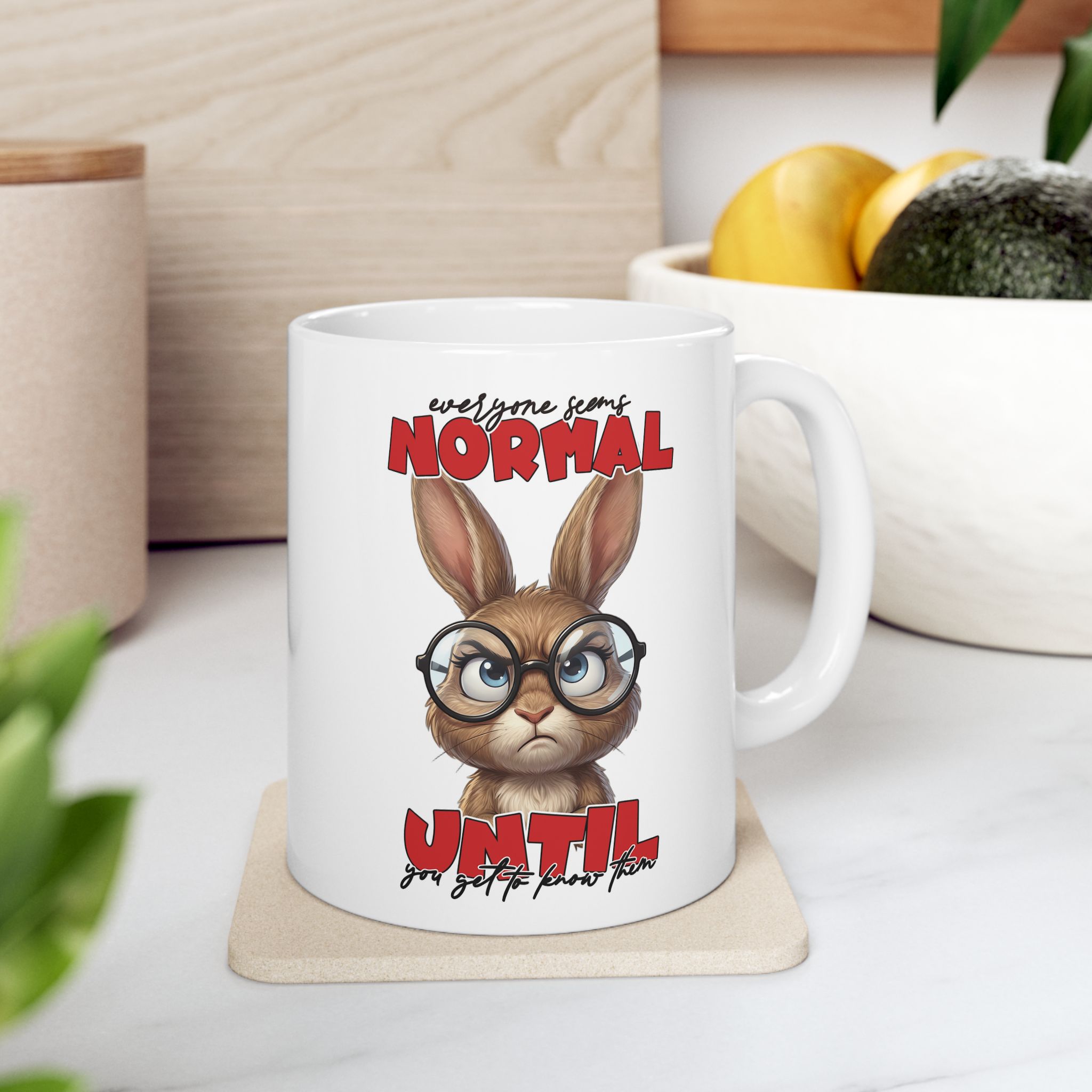White ceramic mug with a grumpy cartoon rabbit wearing glasses, text reads "everyone seems NORMAL UNTIL you get to know them".