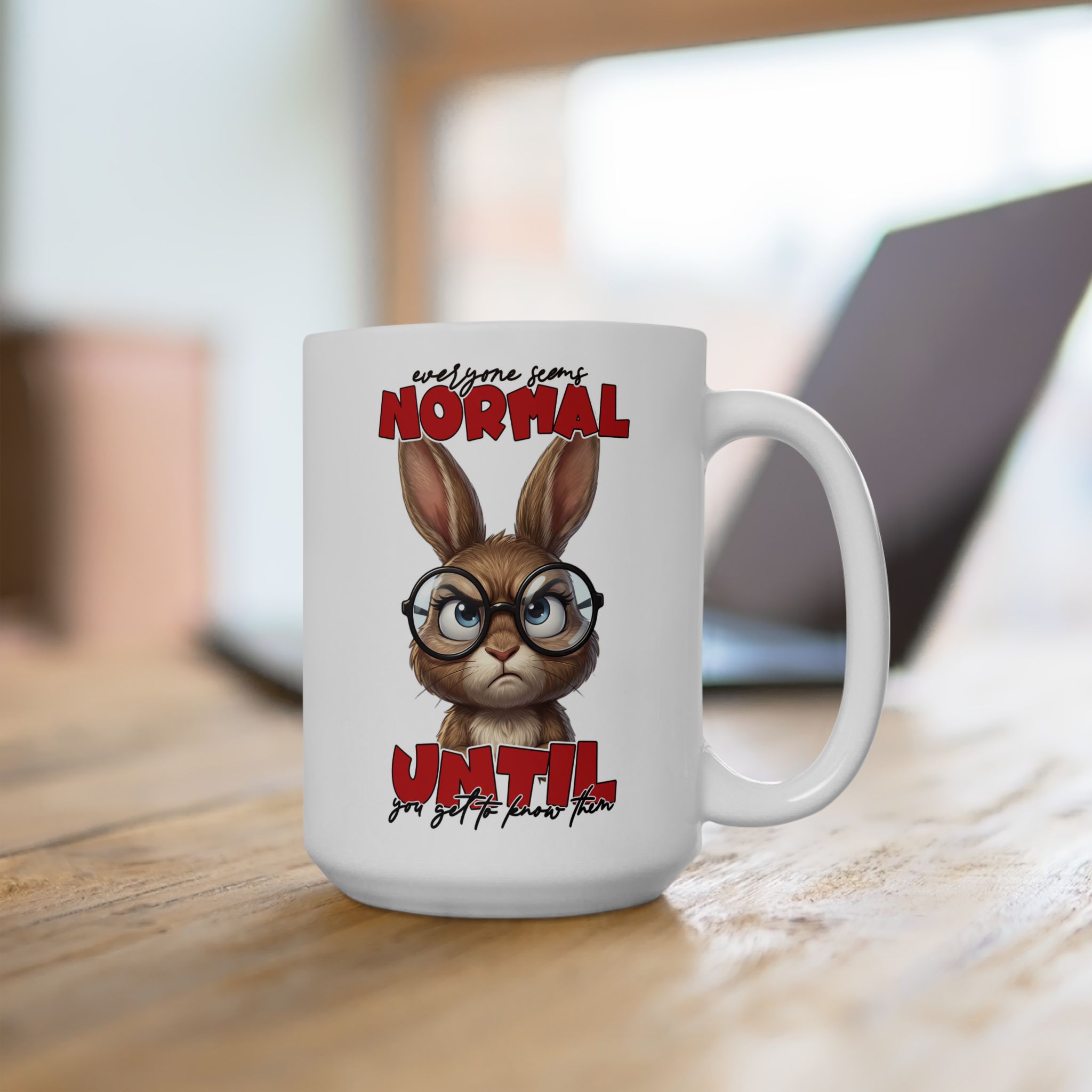 White ceramic mug with a grumpy cartoon rabbit wearing glasses and text that reads "everyone seems NORMAL until you get to know them".