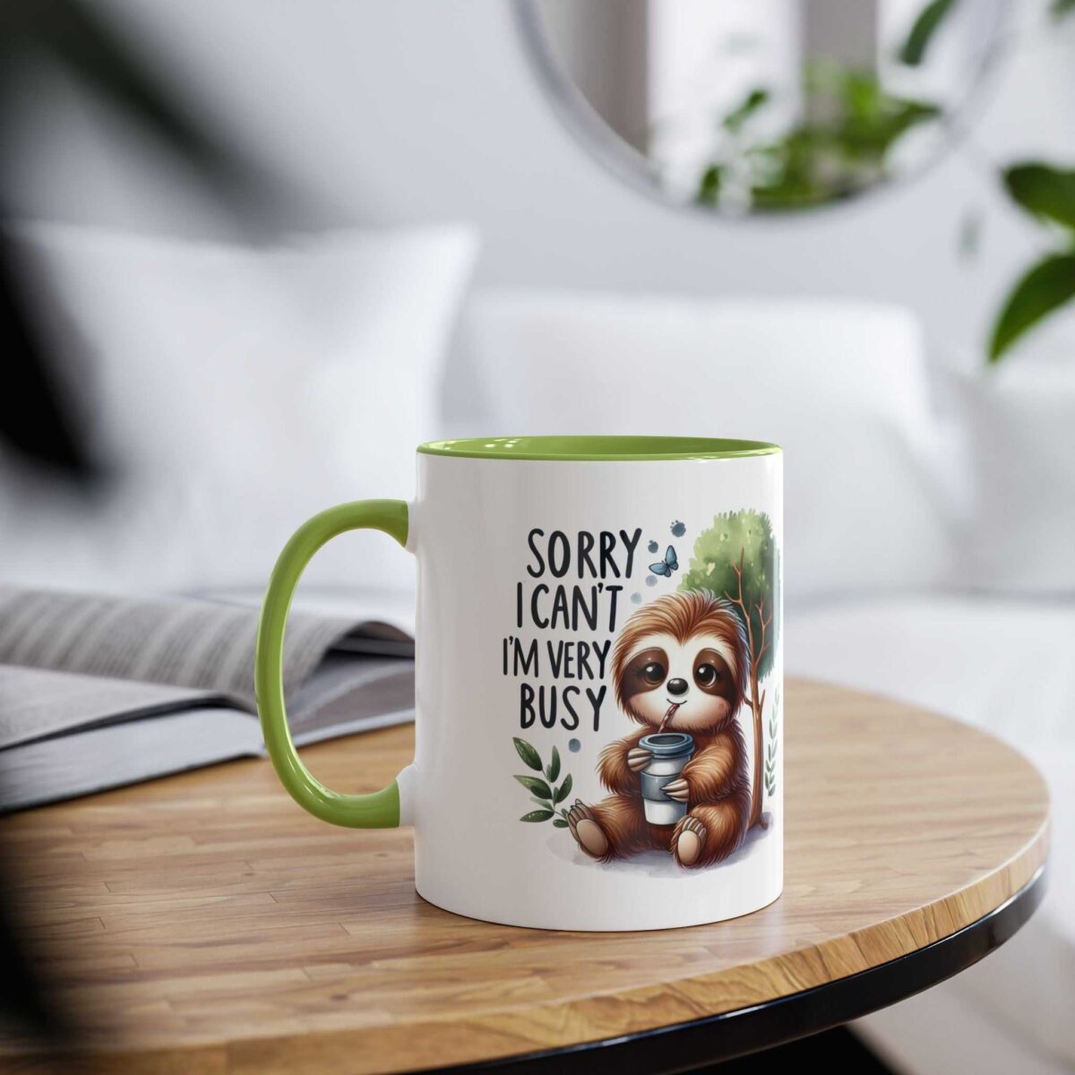 White coffee mug with green handle featuring a cute sloth drinking from a cup and the text 'Sorry I Can't I'm Very Busy'.