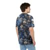 Deep blues and muted creams form a dark floral pattern with skulls and flowing drapery across this tee.