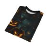 Glowing jack-o'-lanterns, gnarled branches, and falling leaves cover this dark, spooky tee shirt, depicting a haunted forest scene with faint lights.